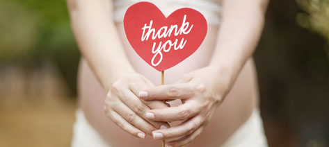 pregnant woman holding heart with a text that says thank you